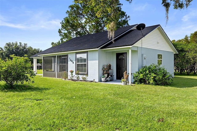 back of house featuring a sunroom, stucco siding, and a yard