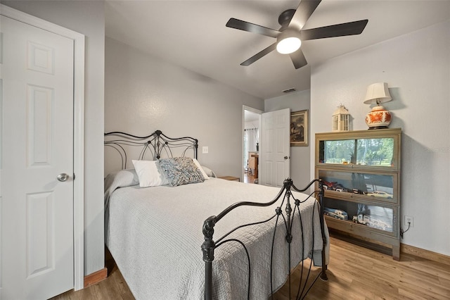 bedroom featuring visible vents, ceiling fan, baseboards, and wood finished floors