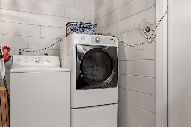 laundry room with laundry area, independent washer and dryer, and concrete block wall