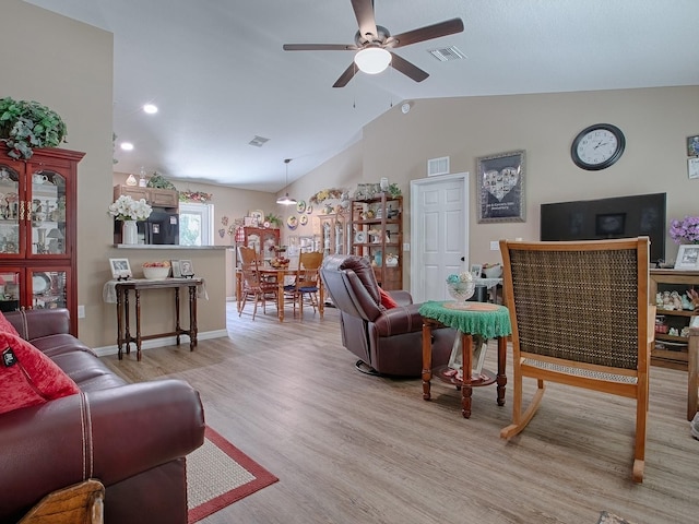 living room featuring ceiling fan, light hardwood / wood-style flooring, and vaulted ceiling