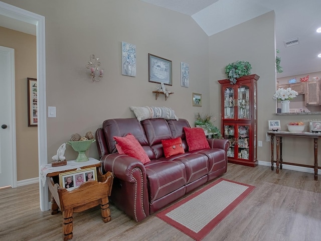 living room featuring lofted ceiling and light hardwood / wood-style floors