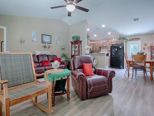 living room featuring ceiling fan, light hardwood / wood-style flooring, and vaulted ceiling