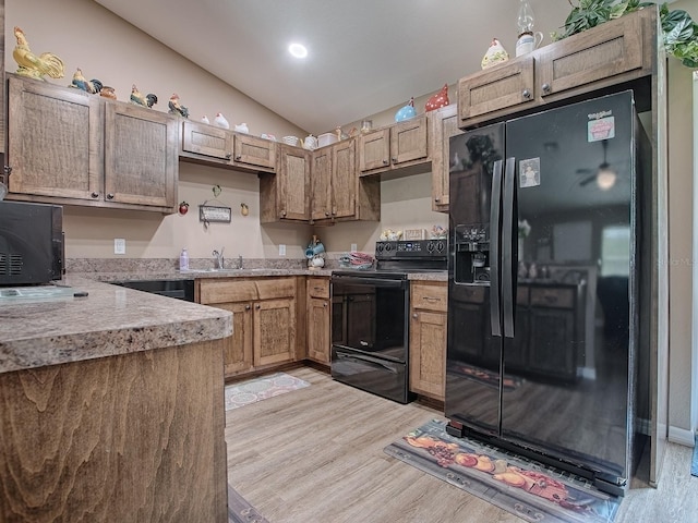 kitchen with light hardwood / wood-style flooring, lofted ceiling, sink, and black appliances