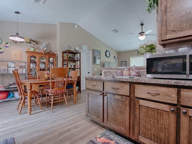 kitchen featuring ceiling fan, light wood-type flooring, vaulted ceiling, and pendant lighting