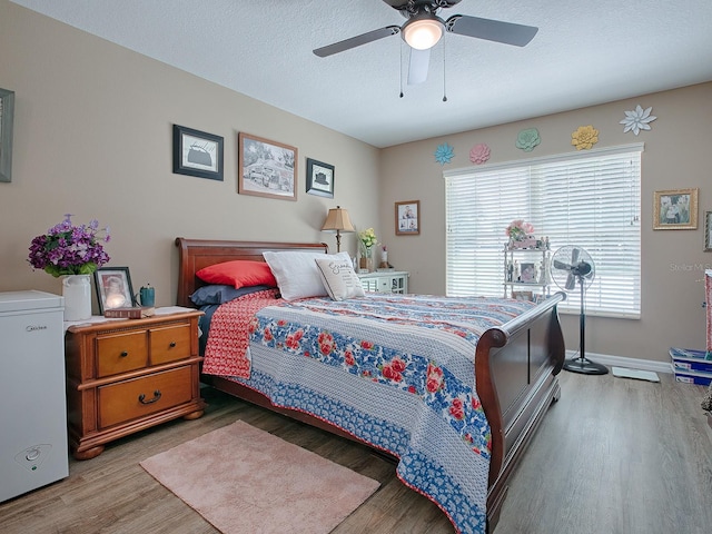 bedroom with ceiling fan, hardwood / wood-style flooring, and a textured ceiling