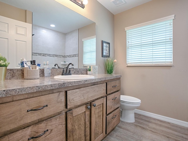 bathroom with toilet, vanity, hardwood / wood-style flooring, and a healthy amount of sunlight