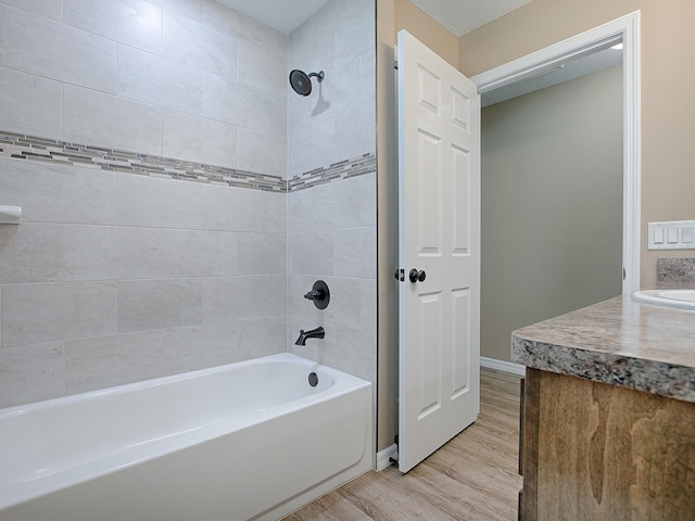 bathroom featuring vanity, hardwood / wood-style flooring, and tiled shower / bath