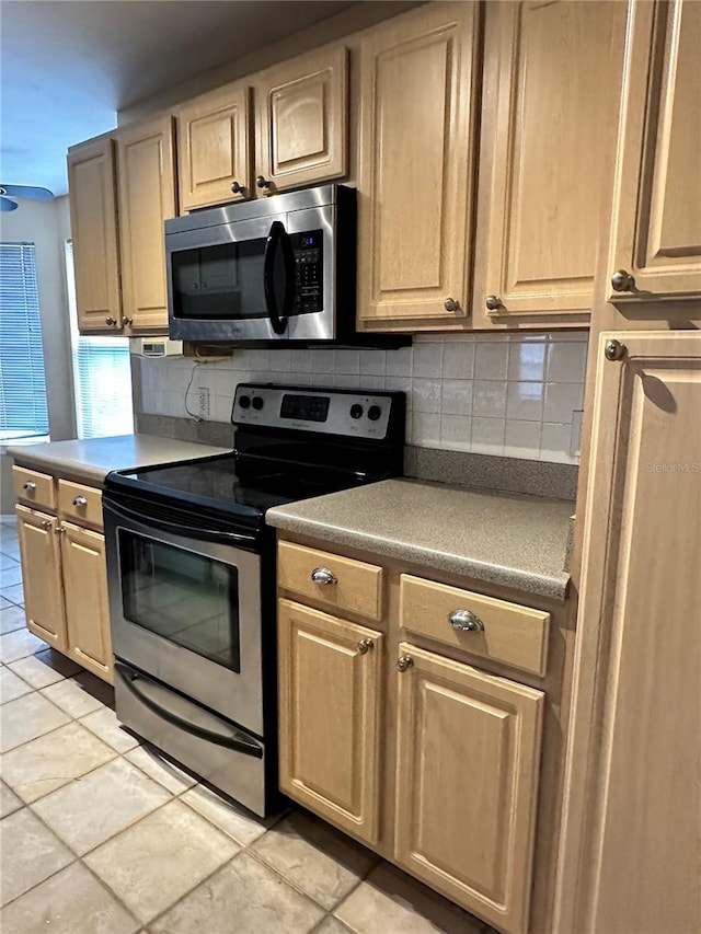 kitchen with light brown cabinetry, backsplash, appliances with stainless steel finishes, and light tile patterned floors