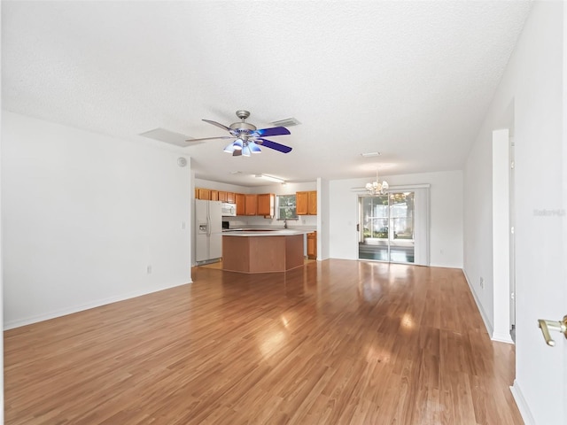 unfurnished living room with a textured ceiling, light hardwood / wood-style flooring, and ceiling fan with notable chandelier