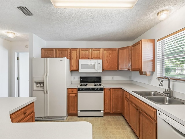 kitchen featuring sink, white appliances, a textured ceiling, and light tile patterned floors