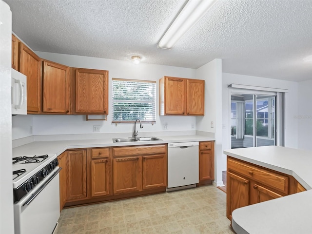 kitchen with sink, a textured ceiling, white appliances, and light tile patterned floors