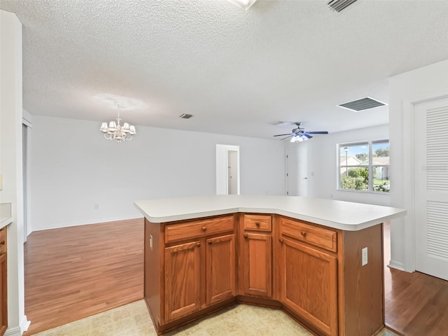 kitchen featuring a center island, ceiling fan with notable chandelier, and light wood-type flooring