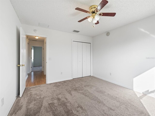 unfurnished bedroom featuring a textured ceiling, carpet flooring, ceiling fan, and a closet