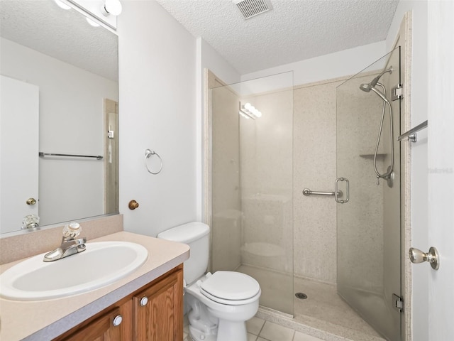 bathroom with toilet, vanity, tile patterned floors, a textured ceiling, and a shower with shower door