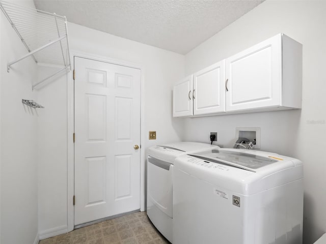 laundry area featuring washer and dryer, a textured ceiling, cabinets, and light tile patterned flooring