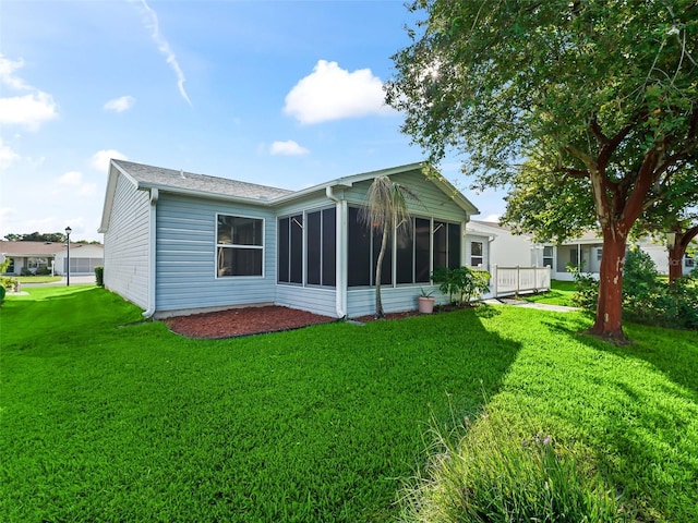 rear view of house with a lawn and a sunroom