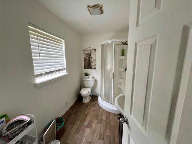 bathroom with a shower with shower door, hardwood / wood-style flooring, and toilet