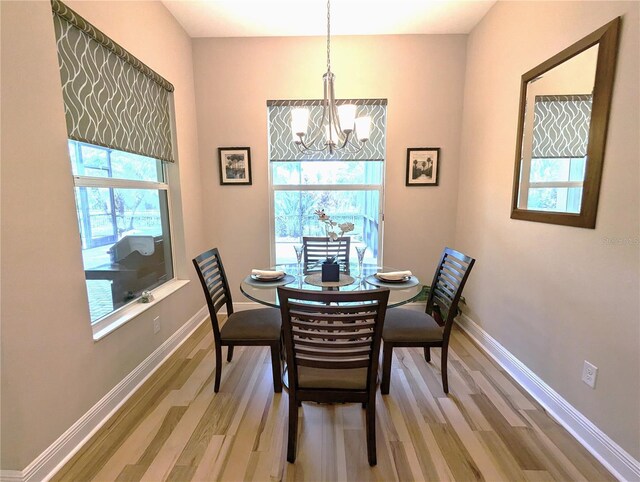 dining space featuring wood-type flooring and an inviting chandelier