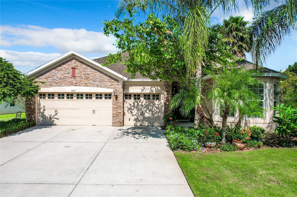 obstructed view of property with an attached garage, stone siding, concrete driveway, and a front yard