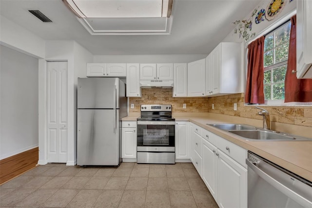 kitchen with light tile patterned floors, appliances with stainless steel finishes, sink, backsplash, and white cabinetry