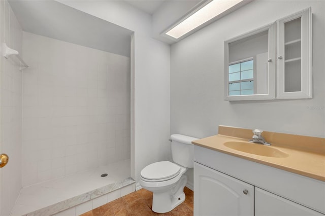 bathroom with tile patterned floors, vanity, tiled shower, and toilet