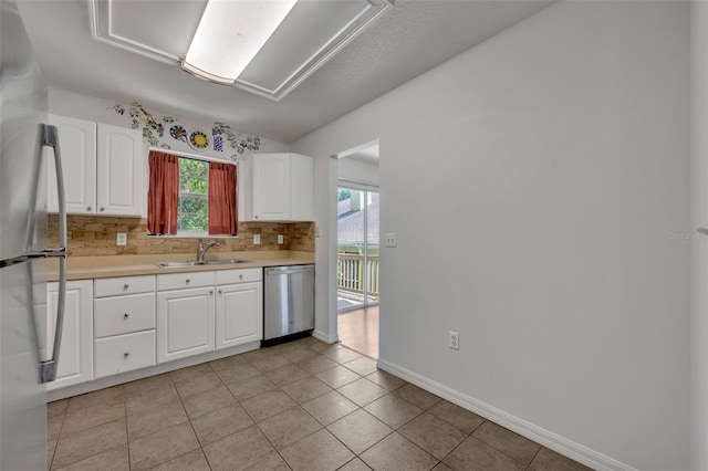 kitchen featuring appliances with stainless steel finishes, light tile patterned flooring, sink, and backsplash