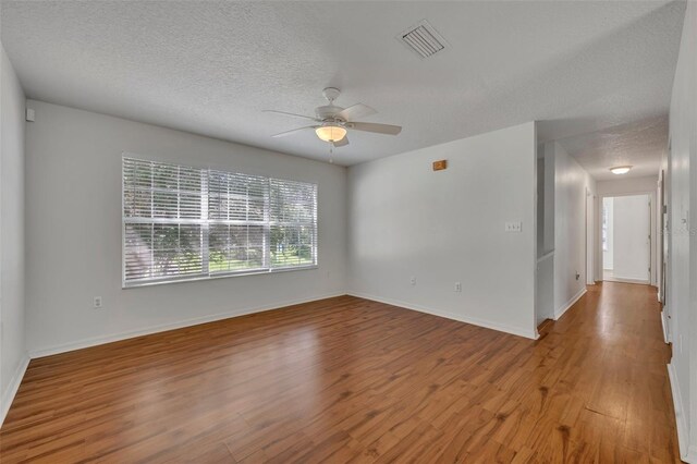 unfurnished room with ceiling fan, wood-type flooring, and a textured ceiling