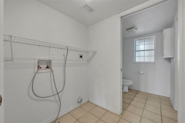 laundry area featuring a textured ceiling, light tile patterned floors, hookup for an electric dryer, washer hookup, and gas dryer hookup