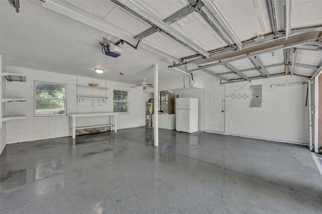 garage featuring a garage door opener, white refrigerator, ceiling fan, electric panel, and water heater