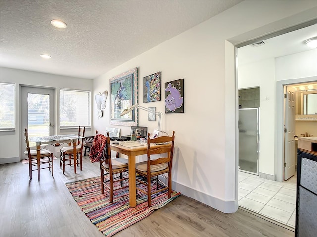 dining area featuring light wood-type flooring and a textured ceiling