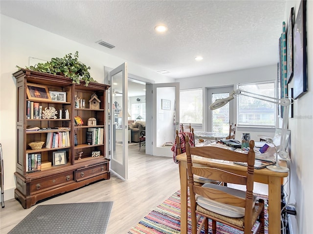 dining area featuring light wood-type flooring and a textured ceiling