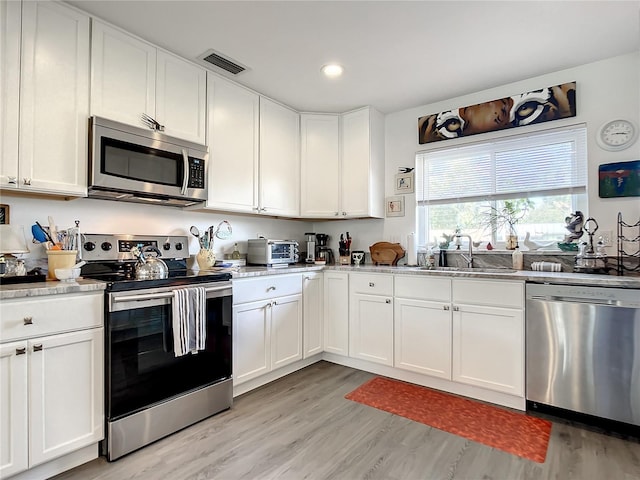 kitchen featuring white cabinets, stainless steel appliances, sink, and light hardwood / wood-style floors