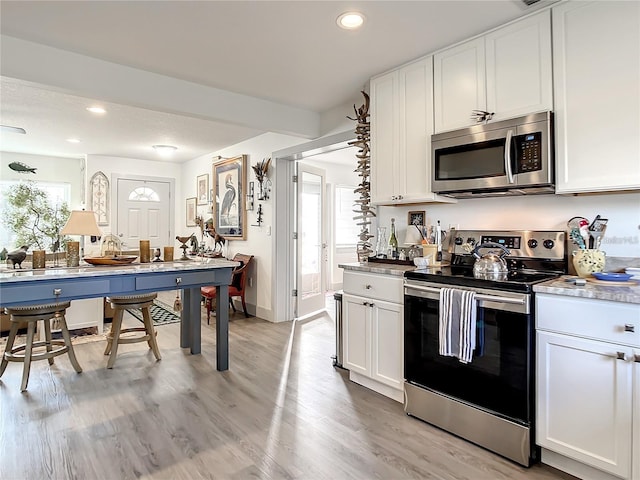 kitchen with appliances with stainless steel finishes, light hardwood / wood-style flooring, and white cabinets