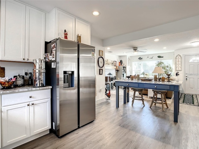 kitchen featuring stainless steel fridge, white cabinets, ceiling fan, and light hardwood / wood-style floors