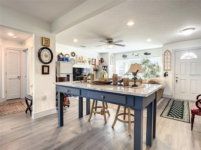 kitchen with ceiling fan, light hardwood / wood-style flooring, and a textured ceiling