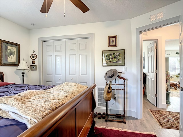 bedroom featuring a textured ceiling, light wood-type flooring, a closet, and ceiling fan