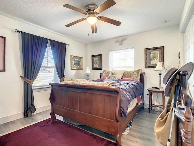 bedroom with ceiling fan, light hardwood / wood-style flooring, and a textured ceiling