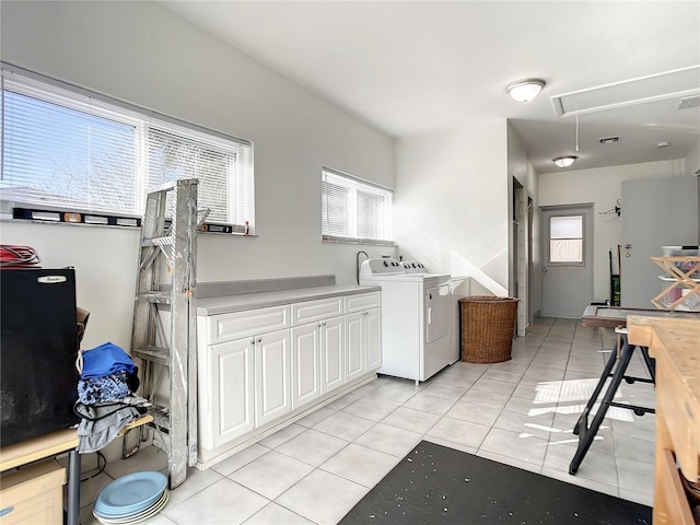 washroom featuring cabinets, washing machine and dryer, and light tile patterned floors