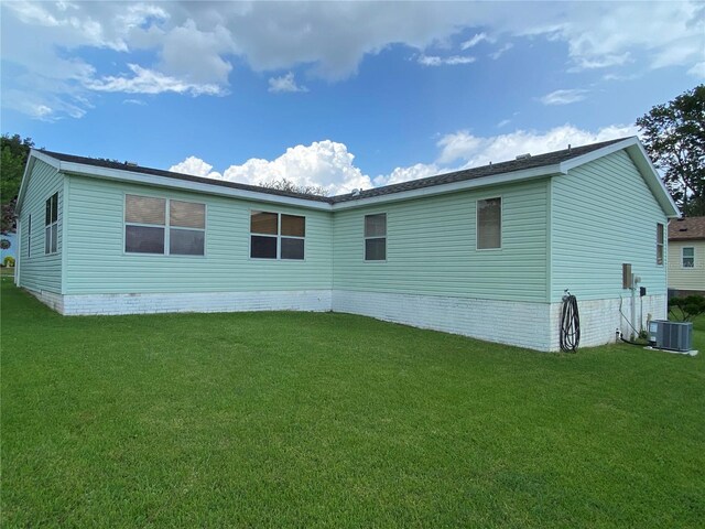 rear view of property featuring a lawn and central AC unit