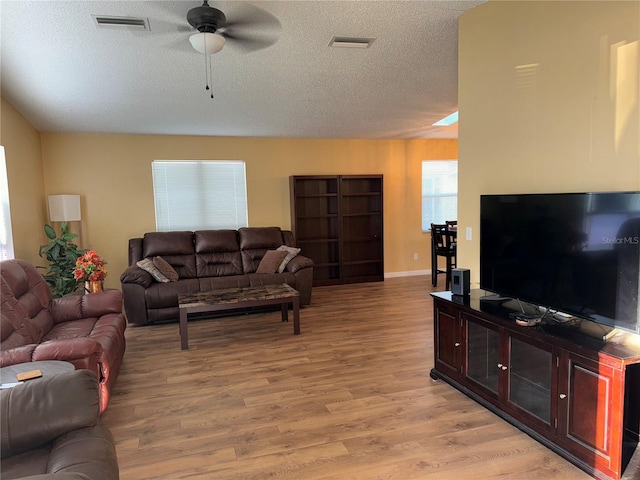 living room featuring ceiling fan, light wood-type flooring, and a textured ceiling