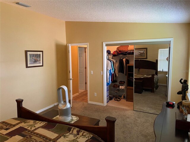 carpeted bedroom with a textured ceiling and a closet