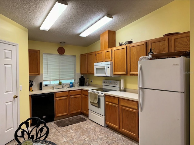 kitchen with light tile patterned flooring, a textured ceiling, white appliances, and sink