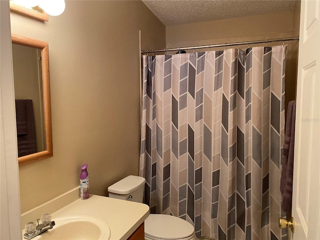 bathroom featuring a shower with shower curtain, vanity, toilet, and a textured ceiling