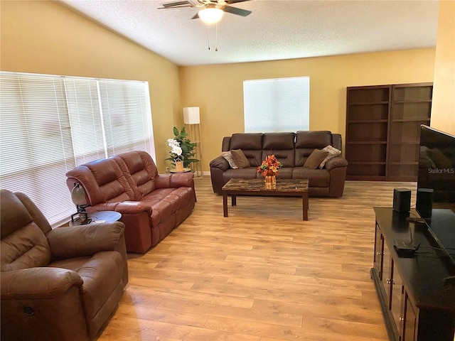 living room featuring ceiling fan, vaulted ceiling, a textured ceiling, and light wood-type flooring