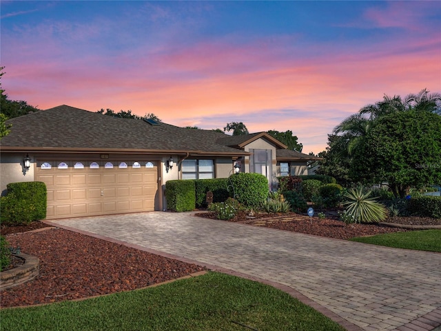 ranch-style house featuring stucco siding, a garage, and driveway