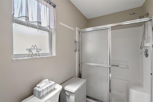 bathroom with a textured ceiling, toilet, and a shower with shower door