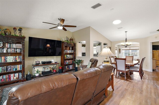 living room with hardwood / wood-style flooring, a textured ceiling, vaulted ceiling, and ceiling fan with notable chandelier