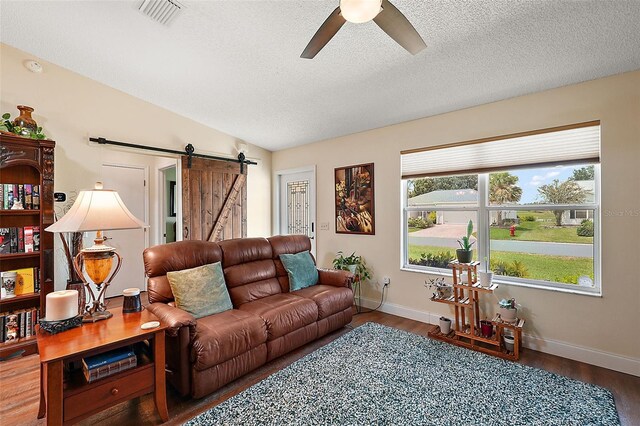 living room featuring a barn door, vaulted ceiling, hardwood / wood-style flooring, and plenty of natural light