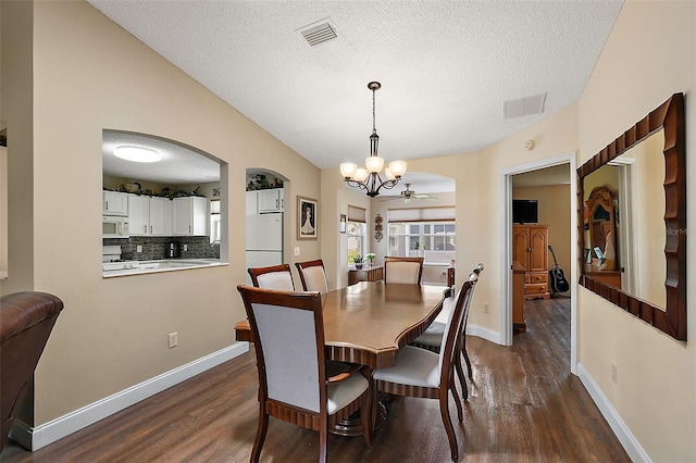 dining space with a textured ceiling, dark wood-type flooring, and a chandelier