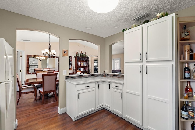 kitchen with hanging light fixtures, dark hardwood / wood-style flooring, a chandelier, and white fridge